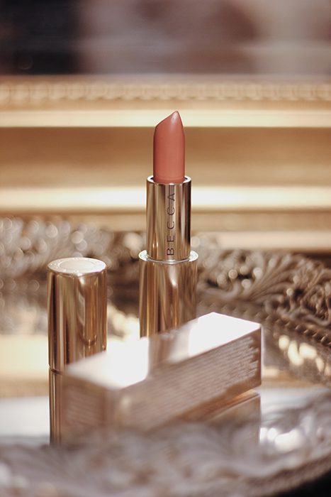 Una elegante foto de un producto de maquillaje de Becca Lipstick en un lujoso plato